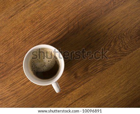 cup of coffee with nice froth on wooden desktop, birds view