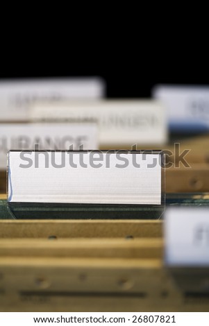 view inside filing cabinet with brown file folders, green folder with blank label in focus. Fill in your own text.