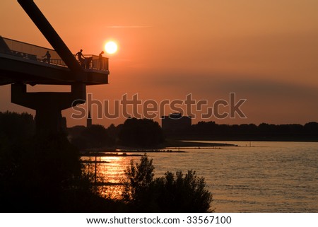 people on bridge watching the sun go down over river rhine at dusseldorf