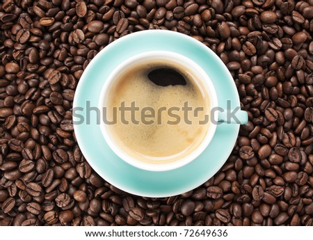 turquoise cup of coffee or espresso  with nice crema on coffee beans background, from above
