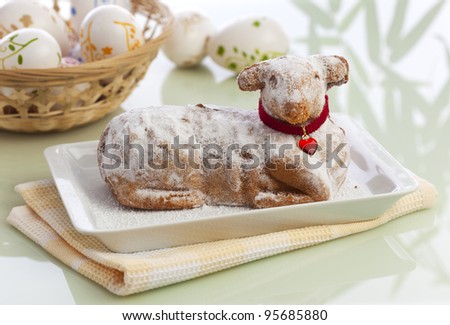 traditional easter lamb cake with powdered sugar, basket full of easter eggs in background