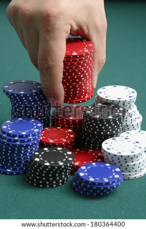 Hand stacking gambling chips on green background