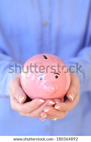 Woman\'s hands holding a pink pig bank
