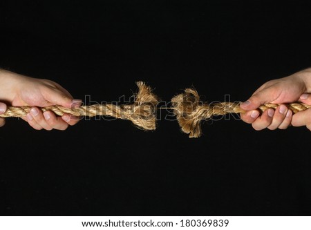 Two hands pulling frayed rope on black background