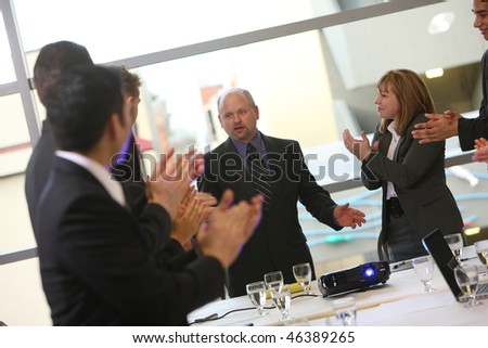 Business people in board room meeting clap for boss
