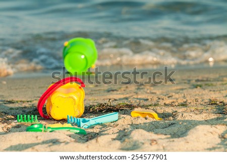 Toy buckets and other toys on a beach near the edge of the waves