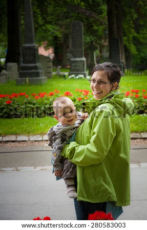 Mother and a baby in a sling carrier smiling inside of a church yard