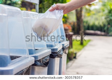 Hand throws away waste material into trash container