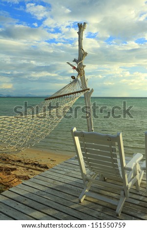 White hammock and wooden beach chair over sea at dusk