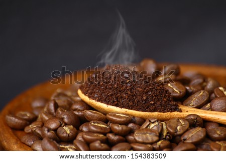 Coffee beans and ground coffee on wooden spoon with grunge background