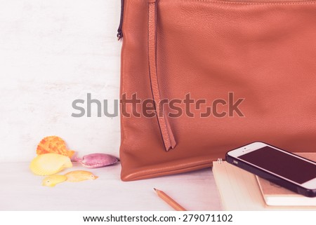 ,mobile phone,notebooks and brown leather bag on grunge white wood background