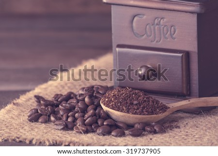 Roasted  coffee beans and ground coffee with grinder on wooden table,instagram filter retro effect