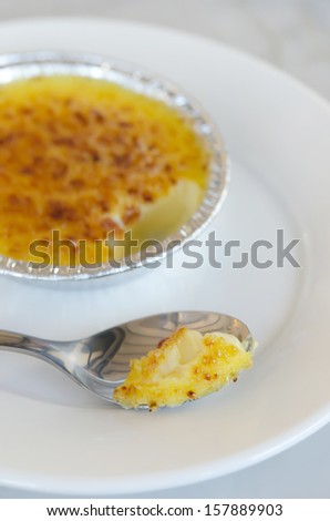 close up caramelized custard with silver spoon ,  creme brulee