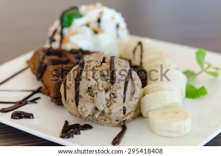 ice cream , banana , chocolate waffles with chocolate sauce and whipping cream