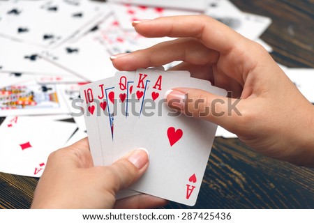 Well-conditioned female hands holding playing cards with poker strongest combination - royal flush