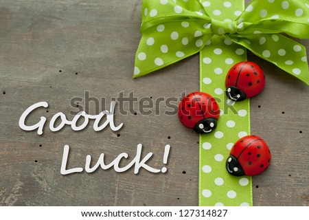 Card with dotted green loop and lady bugs on wooden ground/Good luck/lady bugs