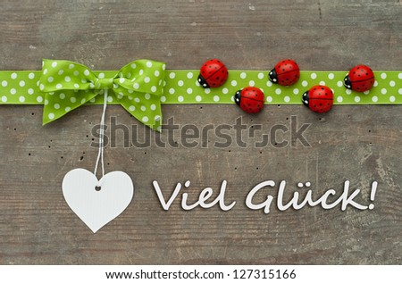 Card with dotted green loop, lady bugs and white heart on wooden ground/card/good luck