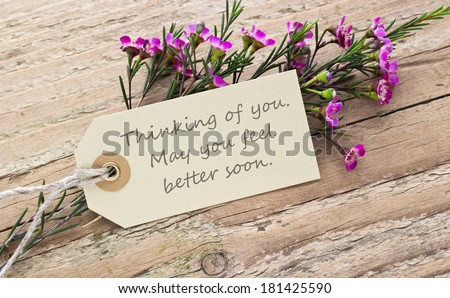 pink flower on a wooden board with card/thinking of you. May you feel better soon./english