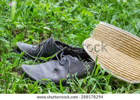 Cap and dusty, black shoes in the grass / to travel / break