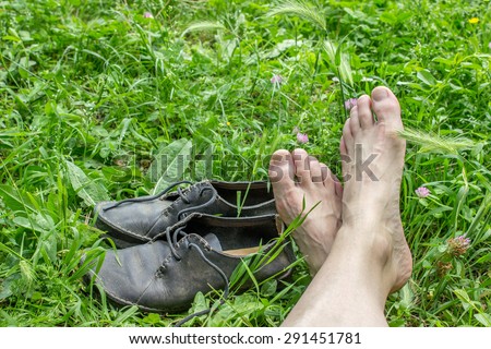 Feet and dusty, black shoes in the grass / to travel / break