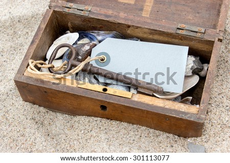 Wooden box with keys, pendants, stones and shells in beach sand / crate and key / beach