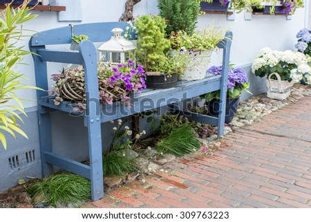 Blue garden bench in front of the house with flowers and decoration / blue garden bench / flowers