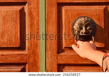 Hand on a handle wooden door to open or close it.