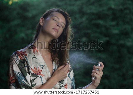 Woman refreshing with thermal water against summer heatwave. Woman spraying body or hair mist, summertime skincare and haircare concept.