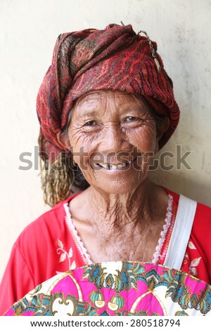 Elderly balinese woman, Ubud, Bali - April 23, 2015: An elderly wrinkled Balinese woman who sells handmade fans on the street, original skin texture, unedited photo.