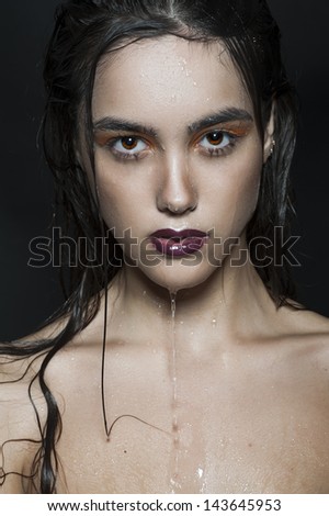 Beautiful young woman in water with wet hair and face. Beauty and fashion.