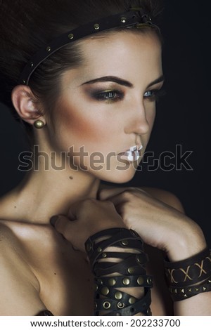 leather Jewellery. Beauty Brunette Egyptian Style Woman with Gold Accessories and Nails. Golden makeup