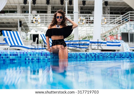 Young beautiful woman making water splash in sexy bikini at the pool.Enjoying summer.