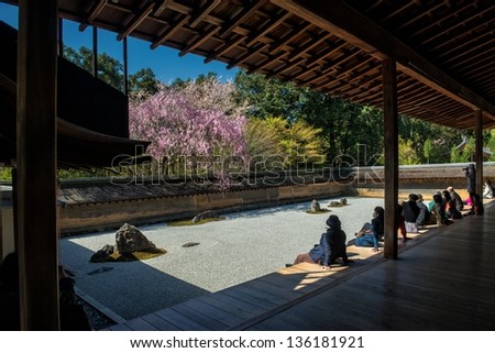 KYOTO, JAPAN - APRIL 8: Tourists meditate at the Zen garden in the Ryoan-ji temple on April 8, 2013 in Kyoto. The world famous rock garden from the 15th century is a UNESCO World Heritage site.