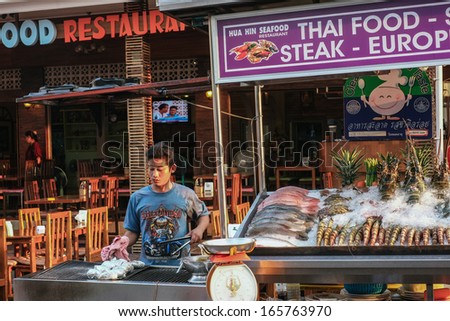 HUA HIN, THAILAND -  FEBRUARY 27: Young Thai man prepares baked potatoes at the night market on February 27, 2013 in Hua Hin. The famous night market in Hua Hin is a major tourist attraction.