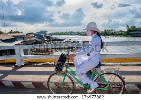 VINH LONG, VIETNAM - MARCH 7: School girl in white school dress bikes home on March 7, 2009 in Vinh Long. Education in Vietnam is divided into five levels from preschool to higher education.