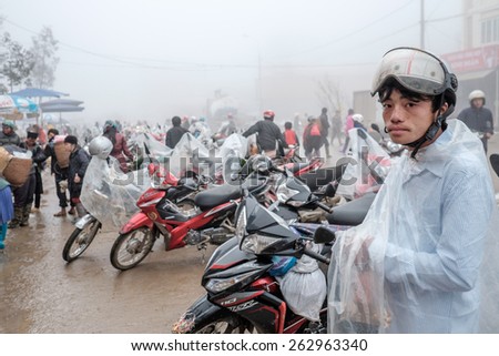 SAPA, VIETNAM â?? FEBRUARY 13: Vietnamese man with a raincoat at a motorbike parking at the market on February 13, 2015 in Sapa. Sapa is famous for its rugged scenery and its cultural diversity.