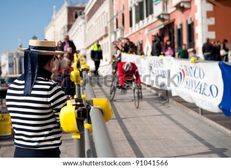VENICE, ITALY - OCTOBER 23: Gondolier applauds a disabled athlete competing in a wheel chair in the Venice Marathon on October 23, 2011 in Venice.