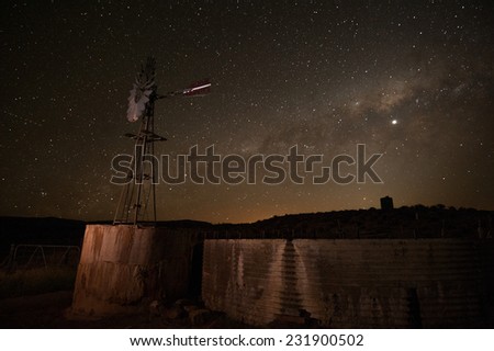 A farm wind pump is seen against the milky way solar system in this night photograph