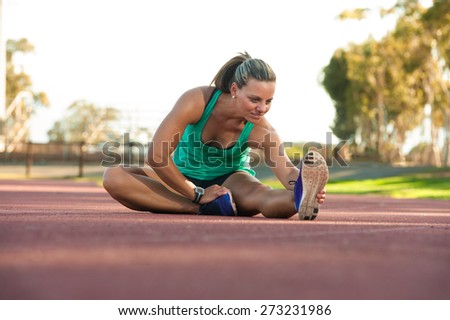 vibrant image of a female athlete stretching on a running track