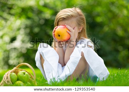 Happy smiling child eating apple  in  park