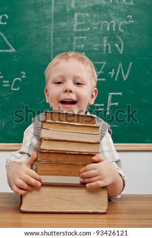 Cheerful smiling  little boy sitting at the table. Looking at camera School concept
