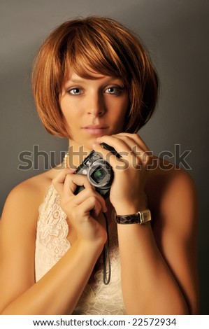 Portrait of beautiful woman with red hair holding compact camera.