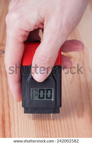 Female hand measuring moisture in wooden wall