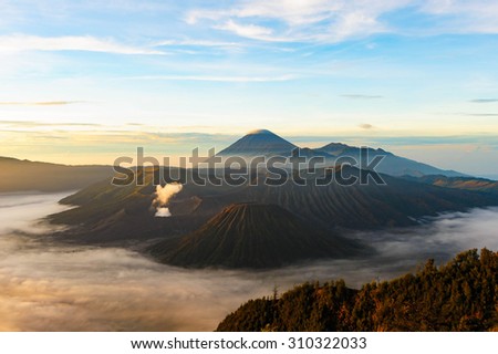 The sweet Mount Bromo,in wide angle while the smoke heart shape and dust coming from the crater in the morning with mist around the floor, warm tone