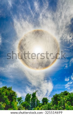 Corona on blue sky, ring around the sun with weird shape cloud.