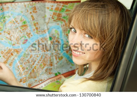 Travel concept - young woman with road map sitting in car enjoy road trip