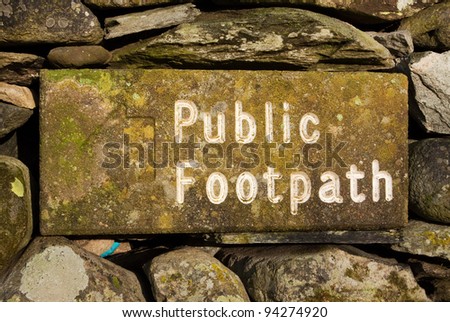 Stone Public Footpath Sign.  The stone public footpath sign is embedded in a dry stone wall and is situated alongside Ullswater lake in the English Lake District.