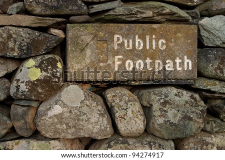 Stone Public Footpath Sign.  The stone public footpath sign is embedded in a dry stone wall and is situated alongside Ullswater lake in the English Lake District.