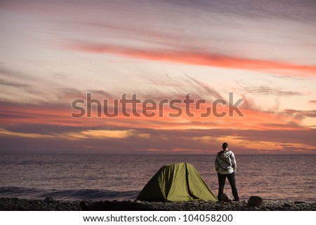 30s years old man near the sea standing and looking at sunset