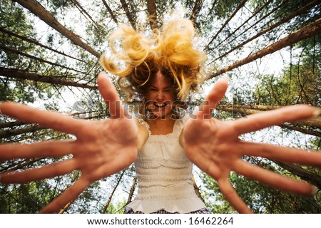 Aggressive woman stretch her hands to camera at piny forest